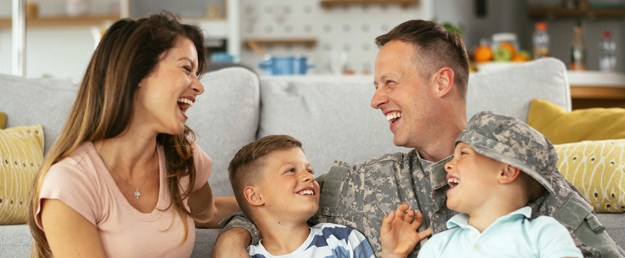 Soldier sitting in couch smiling with wife and kids