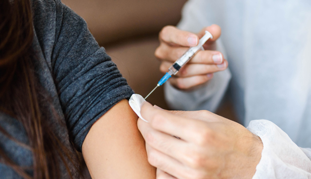 Health provider applying vaccine to young girl